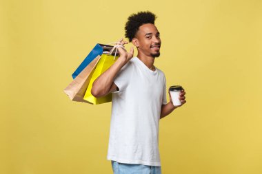 İzole sarı arka plan üzerinde renkli kağıt poşet olan Afrika kökenli Amerikalı adam