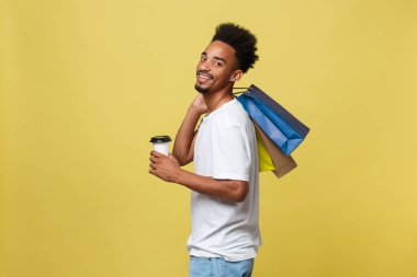 İzole sarı arka plan üzerinde renkli kağıt poşet olan Afrika kökenli Amerikalı adam