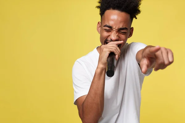 Homem afro-americano elegante cantando em microfone isolado em um fundo de ouro amarelo — Fotografia de Stock