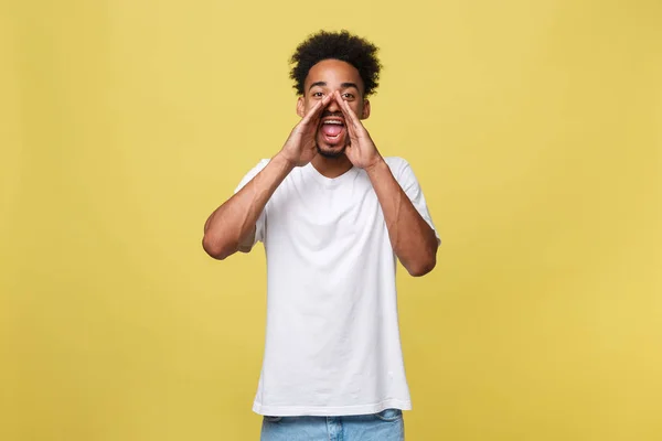 Positiver junger schwarzer Kerl, Student, Arbeiter-Angestellter schreit den Mund weit auf und legt seine Hände als Mundstück vor sein Gesicht. Porträt auf weißem Hintergrund in lässiger Kleidung. — Stockfoto