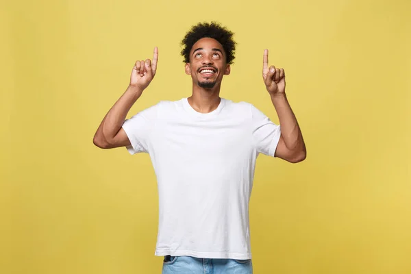 Junger schöner afrikanisch-amerikanischer Mann über gelbem Hintergrund, der nach oben zeigt. — Stockfoto