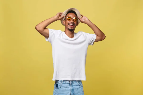 Nahaufnahme Porträt eines jungen Afroamerikaners schockiert Touristen, hält seine Brille, trägt Touristen-Outfit, Hut, mit weit aufgerissenen Augen. — Stockfoto