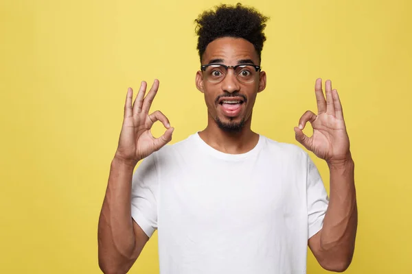 Portrait of happy african-american man showing ok sign and smiling, over yellow background — Stock Photo, Image