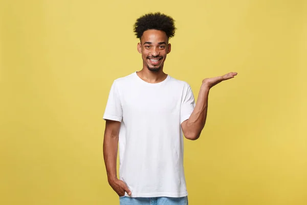 Charmant gut aussehender junger schwarzer Mann hält seine Hand in die Höhe, um das aktuelle Verkaufsprodukt zu zeigen. isoliert über gelbem Hintergrund. — Stockfoto