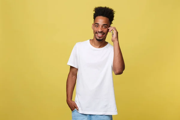 Junger schwarzer Mann lächelt und telefoniert mit Kopierraum auf gelbem Hintergrund. — Stockfoto