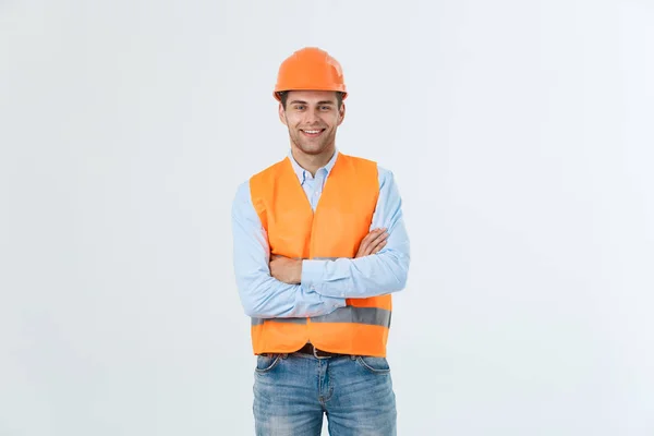 Lachende ingenieur bouwkunde poseren met gekruiste armen. Geïsoleerd over grijze achtergrond — Stockfoto