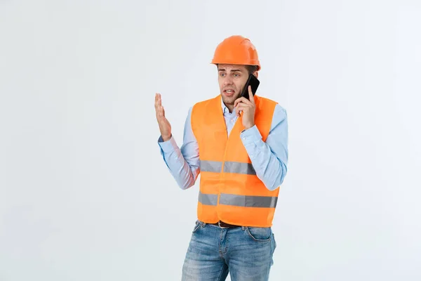 Ingénieur de construction parlant sur un téléphone mobile, homme adulte sérieux utilisant un smartphone pour la communication avec les travailleurs sur le chantier . — Photo