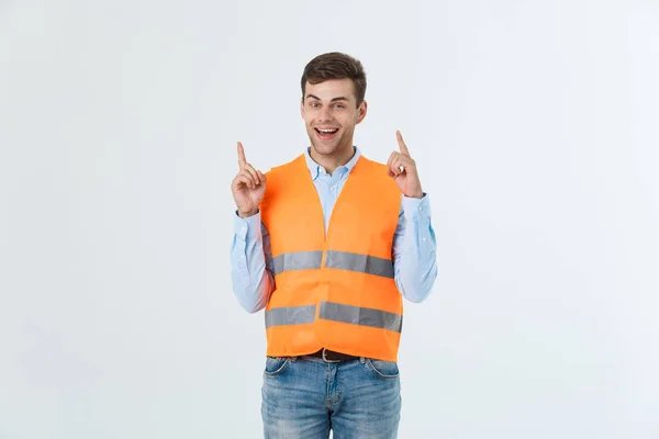 Ung kaukasiska man över vit bakgrund bär entreprenör enhetliga och skyddshjälm överraskade med en idé eller fråga pekande finger med glada ansikte, nummer ett — Stockfoto