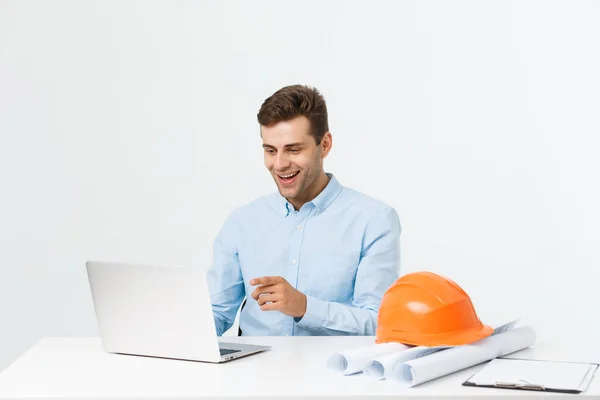 Der gut aussehende männliche Ingenieur arbeitet mit einem Notizbuch. Er sitzt am Schreibtisch und lächelt. Kopierraum auf der Seite. — Stockfoto