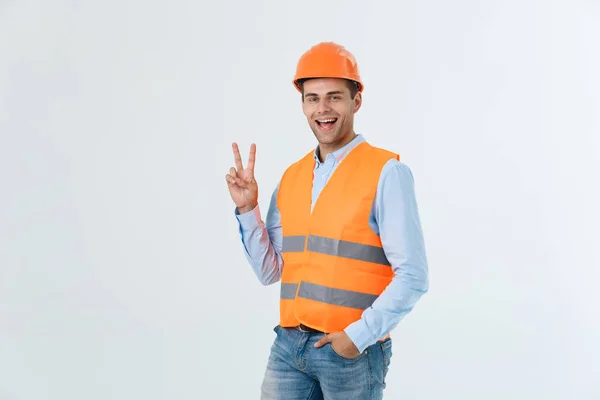 Jovem trabalhador com capacete feliz e contando dois com os dedos no fundo verde — Fotografia de Stock