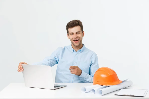 Porträt eines jungen männlichen Innenarchitekten oder Ingenieurs, der lächelnd auf seinem Bürotisch sitzt. — Stockfoto