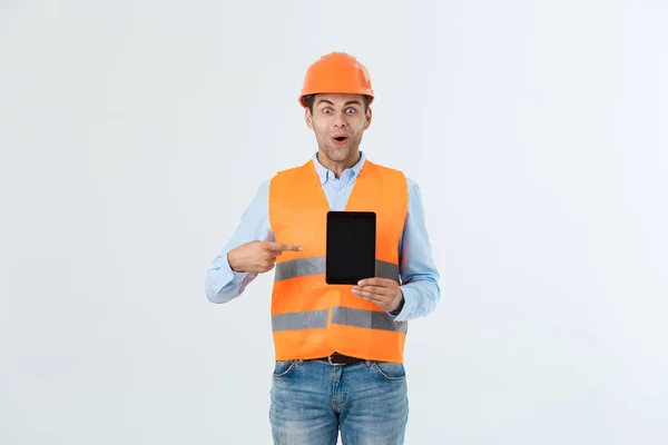 Shocked male engineer showing tablet screen, looks with opened mouth as remembers about important meeting. Male in stressful situation. Surprise and shock concept — Stock Photo, Image