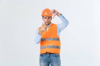 Genç yakışıklı architec adam ile çerçeve elleri ve parmakları ile gülen surat yapma izole arka plan üzerinde güvenlik kask giyiyor. Yaratıcılık ve Fotoğrafçılık kavramı.