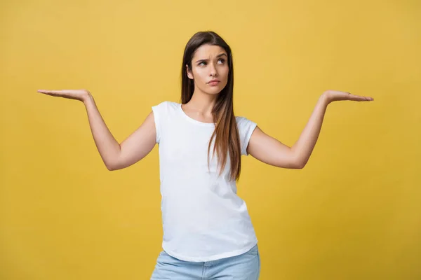 Portret van mooie student, dwaas freelancer, goede positieve vrouw, vriendelijk meisje kijken camera geïsoleerd op gele achtergrond gebaren copyspaces lege plaatsen in twee zijden met palmen — Stockfoto