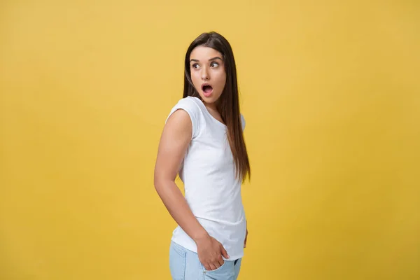 Hermoso retrato femenino de media longitud aislado en el fondo del estudio amarillo. La joven mujer sonriente y sorprendida emocional de pie y mirando a la camera.Las emociones humanas, concepto de expresión facial — Foto de Stock