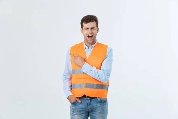 Handsome young professional engineer man over grey wall wearing orange vest amazed and surprised looking and pointing with fingers. — Stock Photo, Image