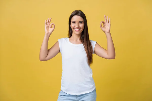 Mujer joven feliz mostrando signo ok con los dedos aislados sobre un fondo amarillo — Foto de Stock