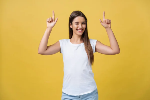 Retrato de jovem linda fêmea com pele perfeita mostrando algo interessante na parede do espaço de cópia para sua informação ou conteúdo publicitário, piscando para a câmera e apontando para cima . — Fotografia de Stock