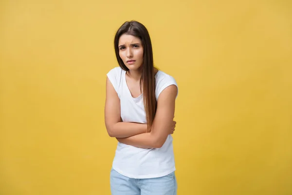 Portrait intérieur de jolie fille debout avec les mains croisées sur le ventre, se sentant maladroit ou souffrant de douleur tout en regardant de côté, debout sur fond jaune. Femme a mal au ventre — Photo