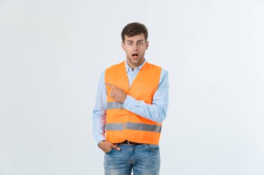 Yakışıklı genç profesyonel mühendis adam Turuncu yelek giyen gri duvarın üzerinden hayran ve parmakları ile işaret şaşırttı.