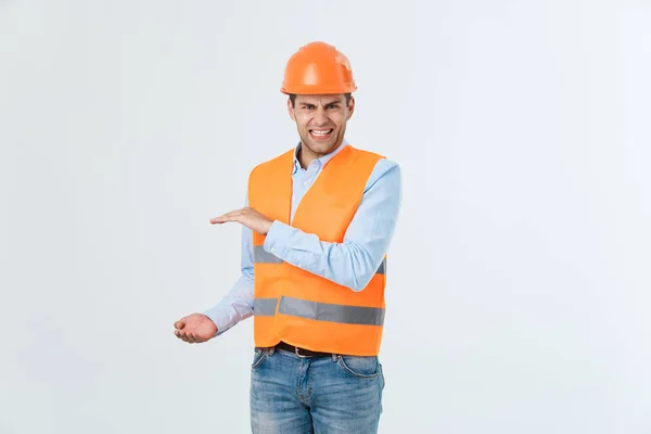 Ingénieur barbe en colère tenant la main sur le côté et expliquant quelque chose, gars portant une chemise caro et un jean avec gilet jaune et casque orange, isolé sur fond blanc — Photo