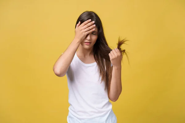 Frau hält ihre langen Haare mit Blick auf beschädigte Splitterspitzen von Haarpflegeproblemen. — Stockfoto