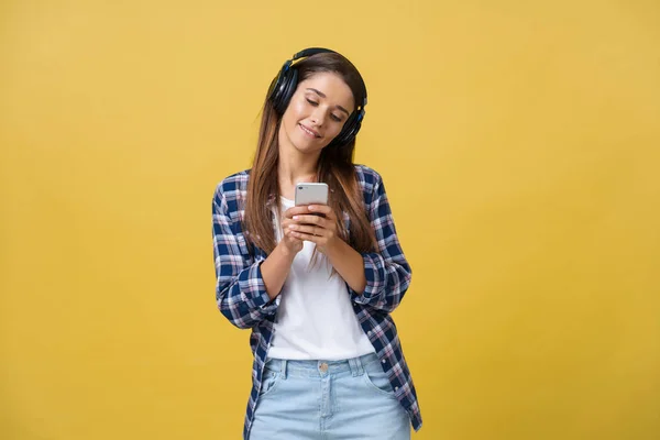 Lifestyle Concept - Portretul unei femei caucaziene frumoase, bucuroasă să asculte muzică pe telefonul mobil. Fundal galben pastel studio. Copiați spațiul . — Fotografie, imagine de stoc