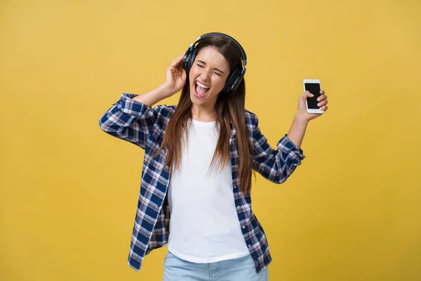 Joven hermosa mujer con auriculares bailando y cantando aislado sobre fondo amarillo — Foto de Stock