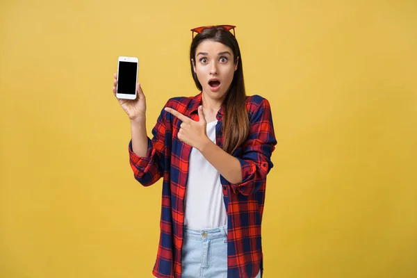 Фото эмоционально шокированной молодой красивой женщины, стоящей в изоляции на жёлтом фоне с помощью мобильного телефона . — стоковое фото