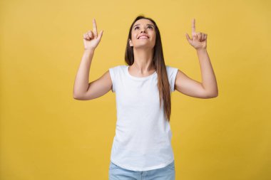 Ayakta ve kamera seyir sarı altın duvar arka plan üzerinde izole kopya alanı üzerinde parmak işaret mutlu genç kadın.