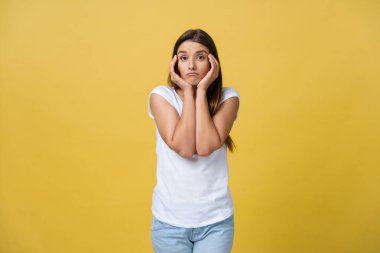 üzgün yalvaran bak genç bir çekici kadın çenesinin altında birbirine bağlı sarı arka plan stüdyo portre ellerinde izole