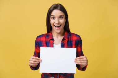 Hayret ya da sarı arka plan üzerinde izole boş beyaz paneliyle sürpriz kız.