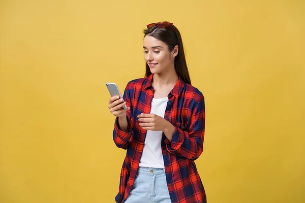 Porträtt av vacker ung kvinna med mobiltelefon isolerad på gul bakgrund — Stockfoto