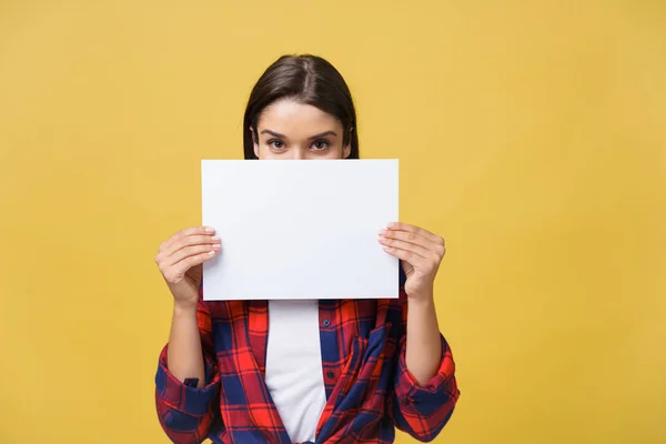 Banner sign kvinna kikar över kanten av tomma tomma papper med kopia utrymme för text. Vackra kaukasiska kvinna som tittar förvånad och rädd - roliga. Isolerad på gul bakgrund. — Stockfoto