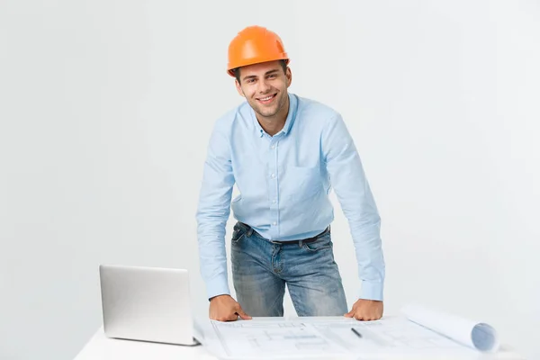 Confiante no seu novo projecto. jovem engenheiro e arquiteto homem trabalhando no laptop e olhando para a câmera com sorriso enquanto estava em seu escritório — Fotografia de Stock