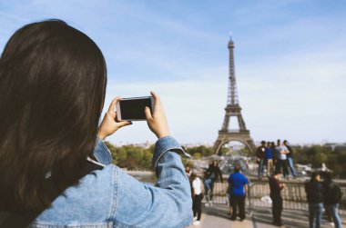 Kadın turist alarak fotoğraf güneş ve mavi gökyüzü altında Paris Eiffel tower yakınındaki telefonla. Dünyanın ünlü popüler bir turistik yer.