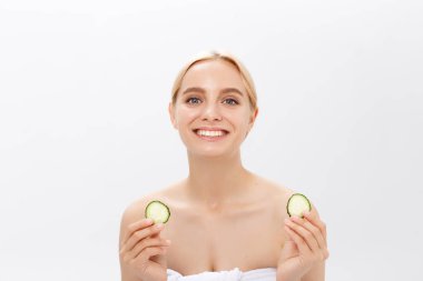 Güzel kadının temiz sağlıklı cilt ve salatalık dilimleri ile yakın çekim yüz. Beyaz izole.