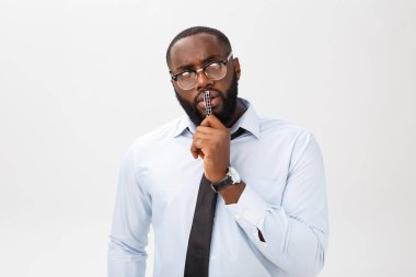 Elindeki kalemle gri takım düşüncesinde dalgın bir Afrikalı-Amerikalı işadamı portresi.