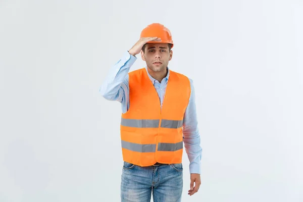 Jonge knappe sarchitects man met veiligheidshelm dragen over geïsoleerde achtergrond met de hand die betrekking hebben op hoofd op zoek naar iets. — Stockfoto