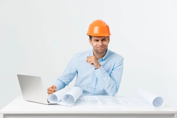 Portrait of confused male designer or architect, feels stressed, being nervous, keeps hand on head, stares in blueprint. Exhausted man creates construction project alone, has some troubles — Stock Photo, Image