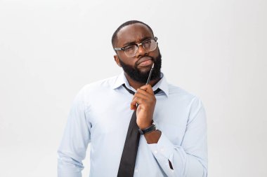 Elindeki kalemle gri takım düşüncesinde dalgın bir Afrikalı-Amerikalı işadamı portresi.