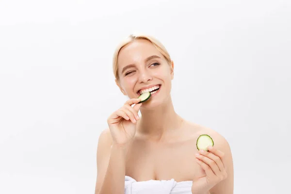 Gros plan sur le visage d'une belle femme à la peau fraîche et propre et aux tranches de concombre. Isolé sur blanc . — Photo