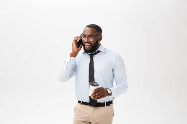 Bra prat. Glada unga afrikanska mannen i vit skjorta som håller en kopp kaffe och prata på mobiltelefonen — Stockfoto