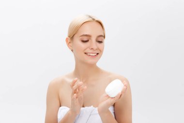 Yüz kremini uygulamadan bir gülen güzel yarı çıplak kadın güzellik portresi kapatmak ve seyir uzağa beyaz arka plan üzerinde izole.