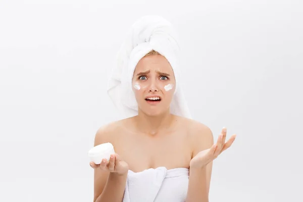 Disappointed young woman with foam on the face and a cream in her hand. — Stock Photo, Image