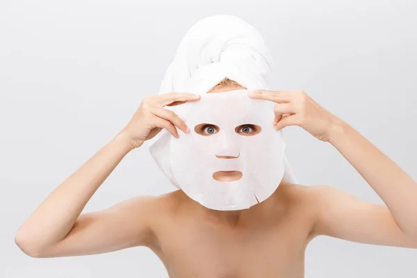 Ομορφιά δέρμα φροντίδα έννοια - όμορφη γυναίκα Καυκάσιος εφαρμογή μάσκας φύλλο χαρτιού σε φόντο λευκό πρόσωπο της. — Φωτογραφία Αρχείου