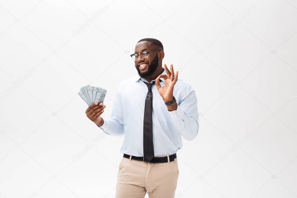 young cheerful black businessman holding and pointing at money isolated on white.