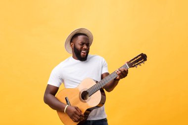 Akustik gitar üzerinde sarı arka plan izole çalmaya gitarist yakışıklı Afro-Amerikan retro tarz.