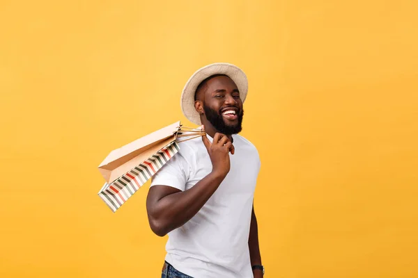 Щасливі афро-американських чоловік тримає сумками на жовтому фоні. Концепція свята — стокове фото