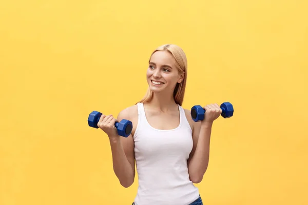 Fitness woman lifting weights smiling happy isolated on yellow background. Fit sporty Caucasian female fitness model. — Stock Photo, Image